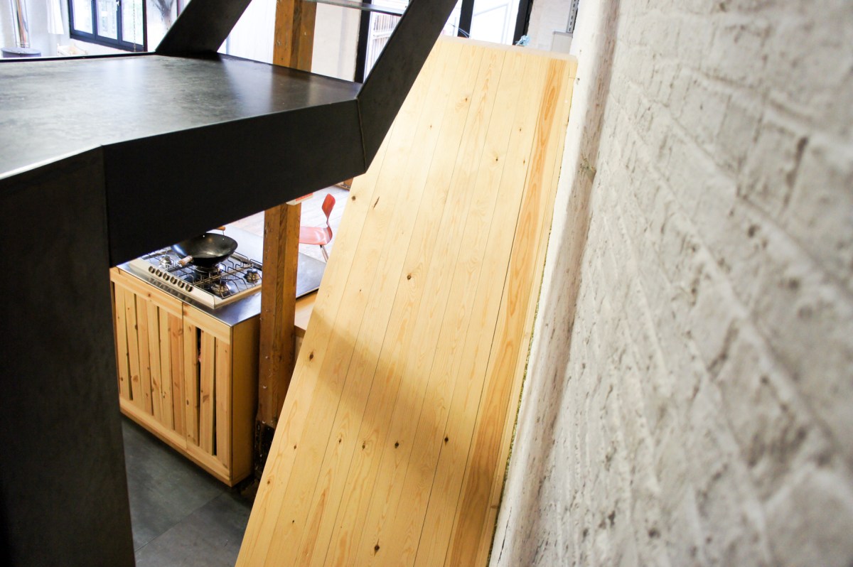 Atelier Antipode See-through kitchen doors in pine wood. The wooden laths are set up in an alternating zig zag pattern. Top view to staircase cover.