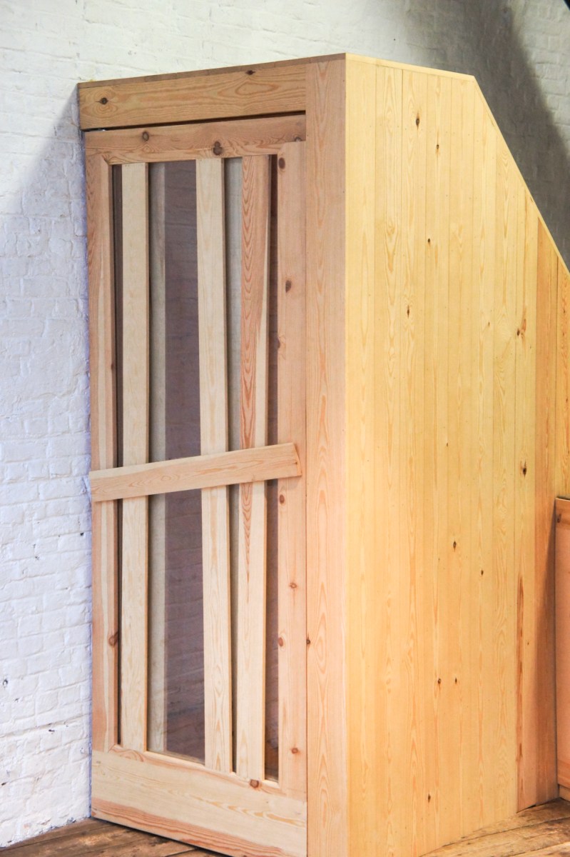 Atelier Antipode See-through pivoting door in pine wood. The wooden laths are set up in an alternating zig zag pattern.