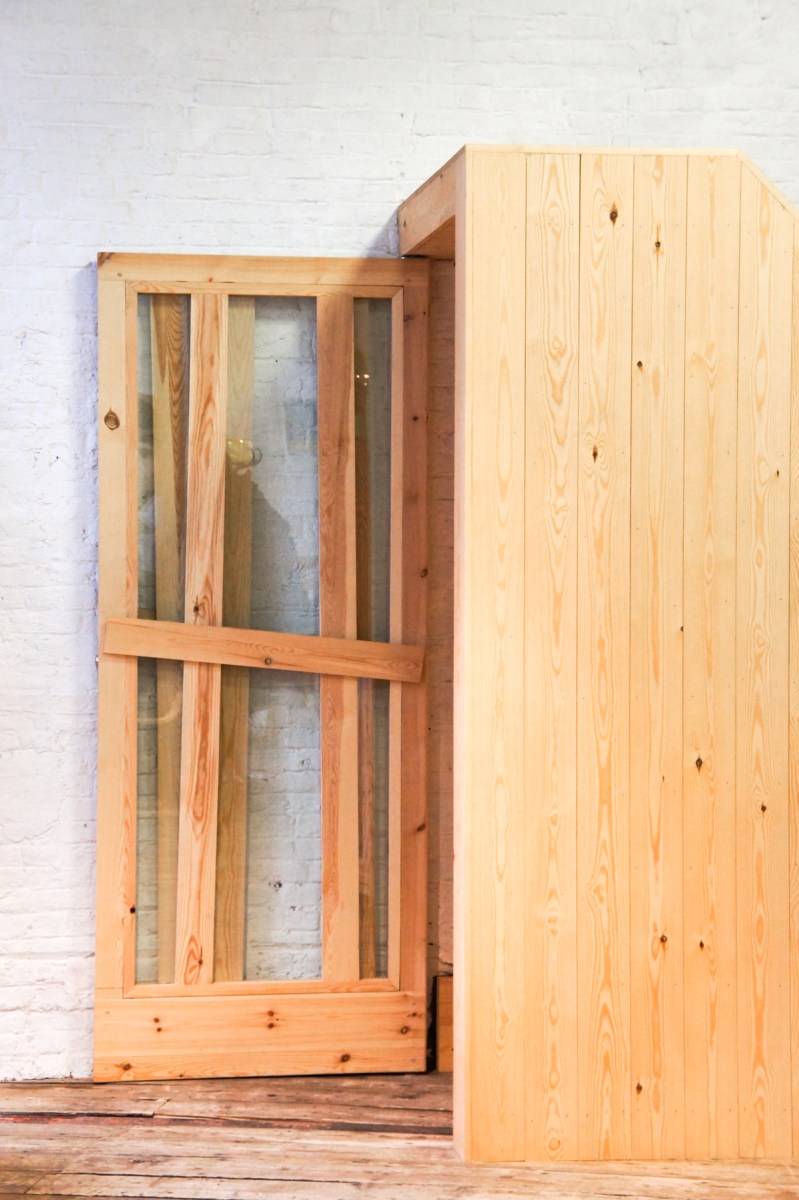Atelier Antipode See-through pivoting door in pine wood. The wooden laths are set up in an alternating zig zag pattern.